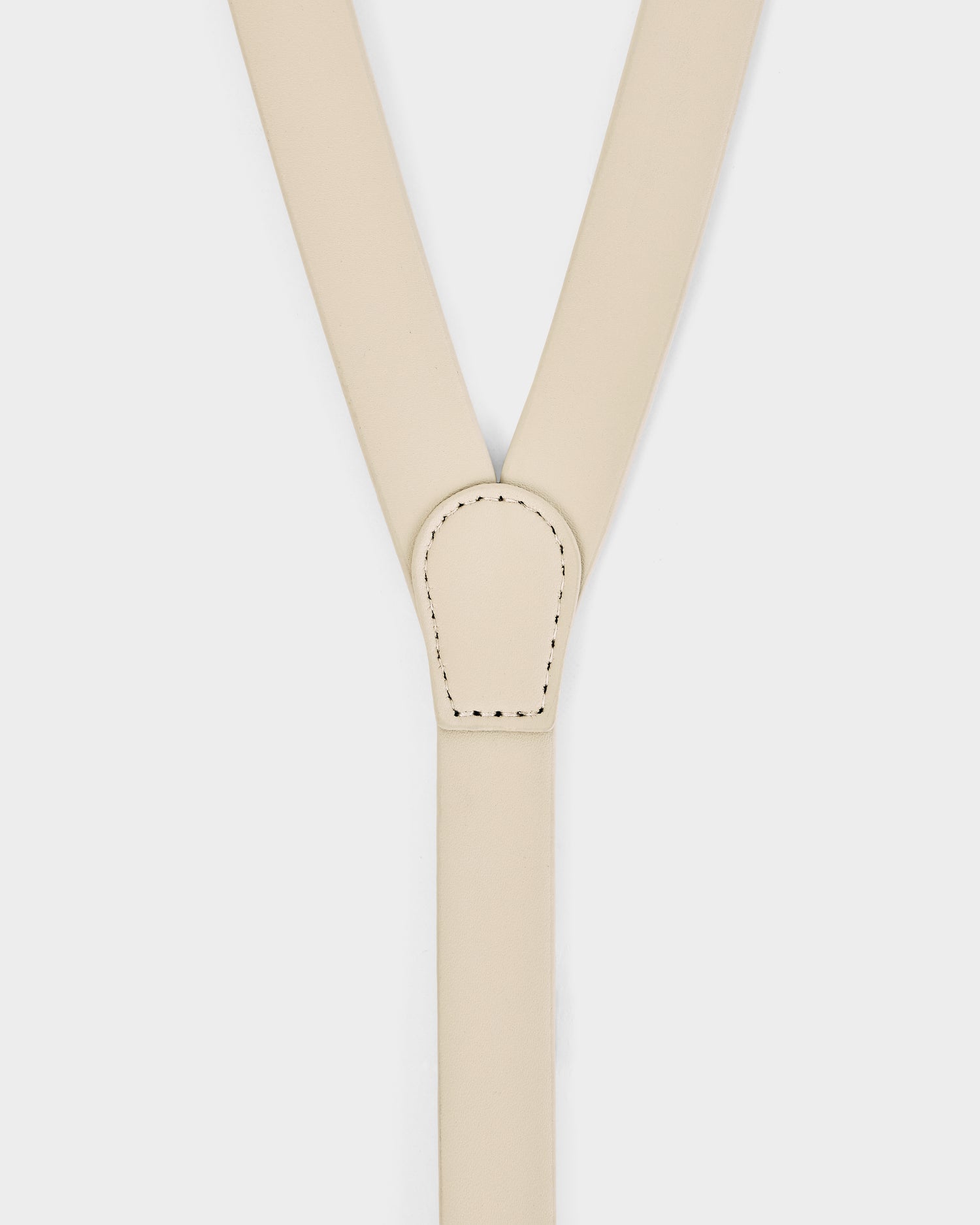 Close-up of Rudsak RAYNA - 8425539 Vanilla suspenders in beige leather, Y-shaped with black stitching at the strap junction. Set against a plain white background.