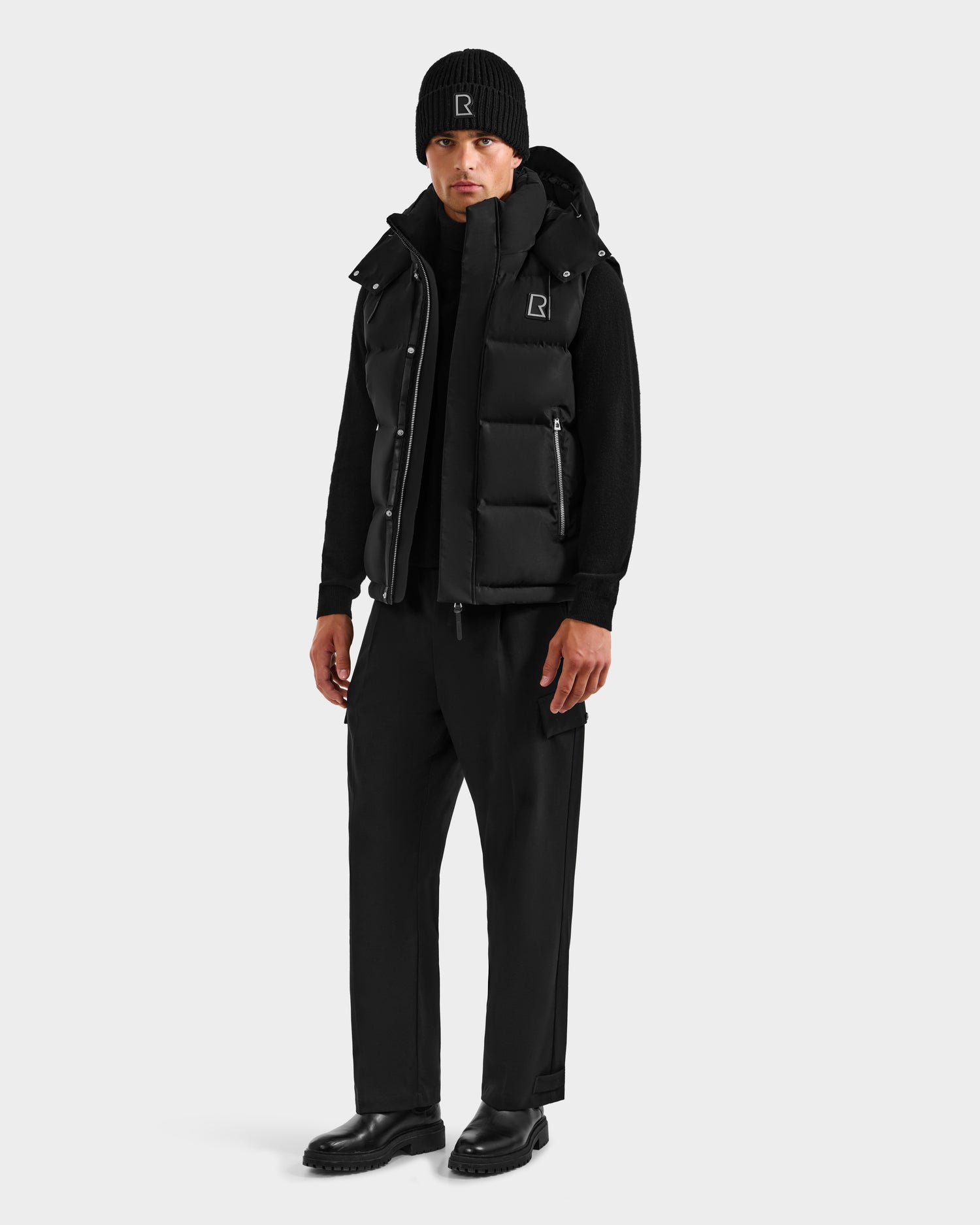A man wears the Rudsak REN H - 6125688 Black men’s quilted down puffer vest and hat, highlighting a stylish and essential cold-weather look.