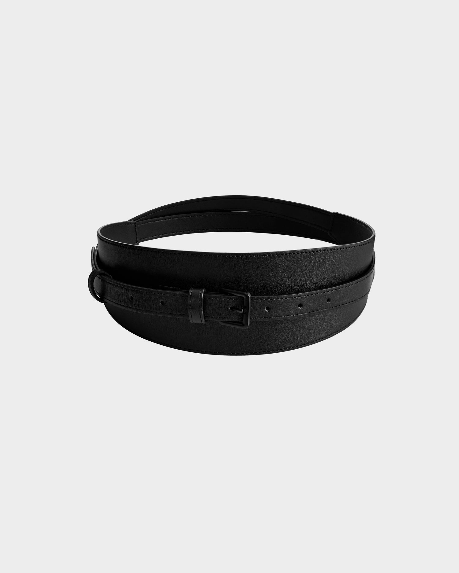 The Rudsak RENA - 8425039 Black is a black leather belt with a rectangular metal buckle, displayed coiled on a plain light gray background.