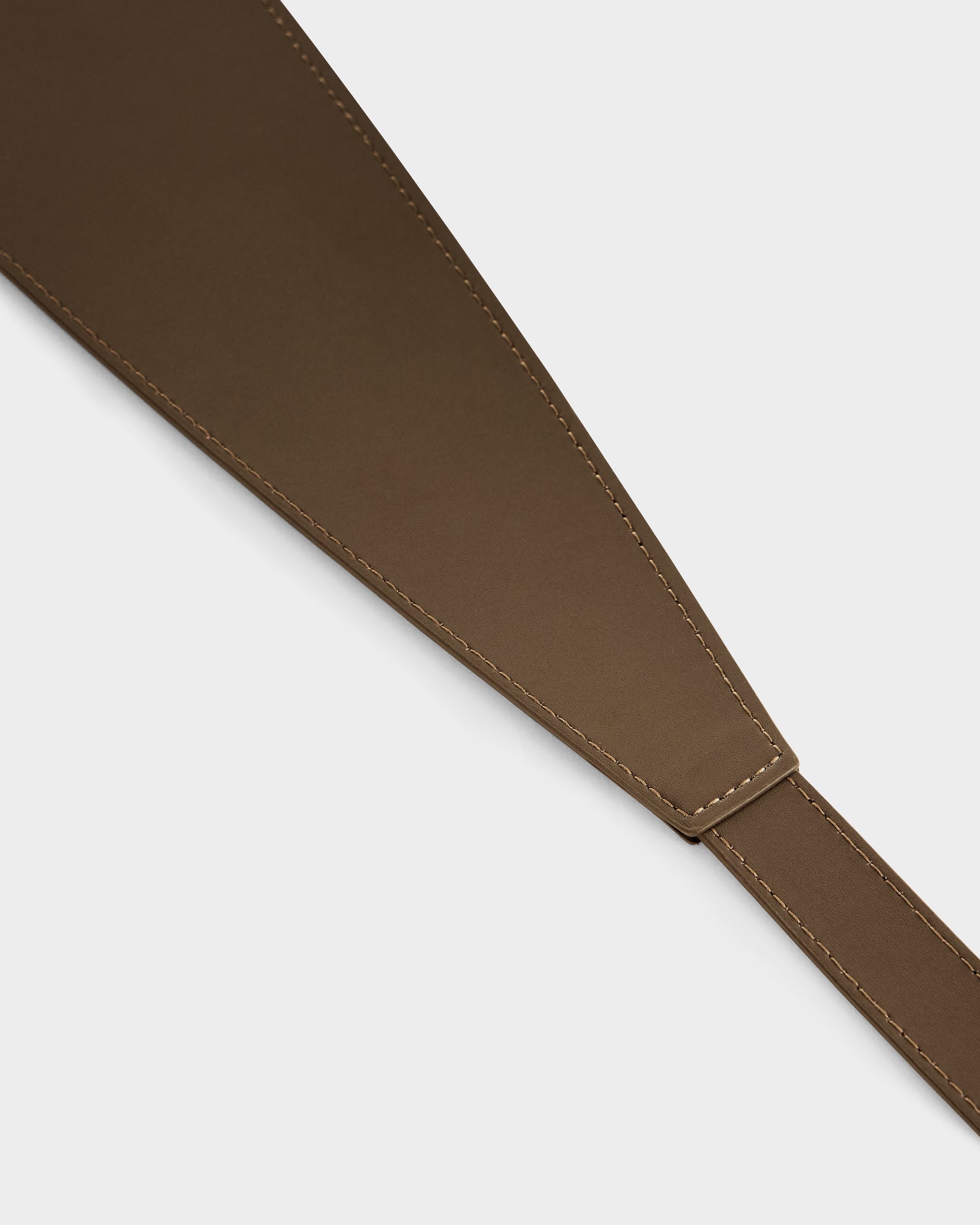Close-up of the Rudsak RENA - 8425039 Mocha brown leather belt, featuring visible stitching and a broad, tapered end that narrows, shown against a plain white background.