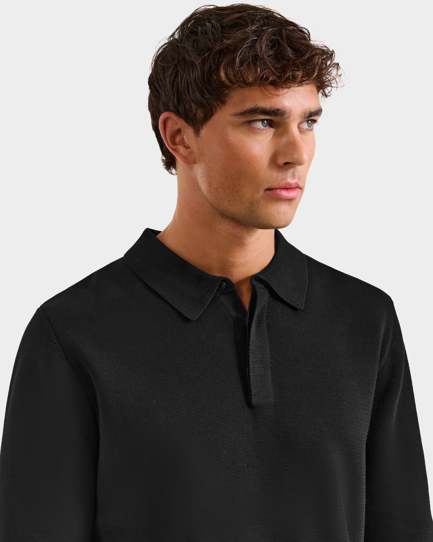 A young man with short brown hair wears the Rudsak RICHARD - 6524529 Black men's knit polo sweater, looking slightly to his right against a plain light background.