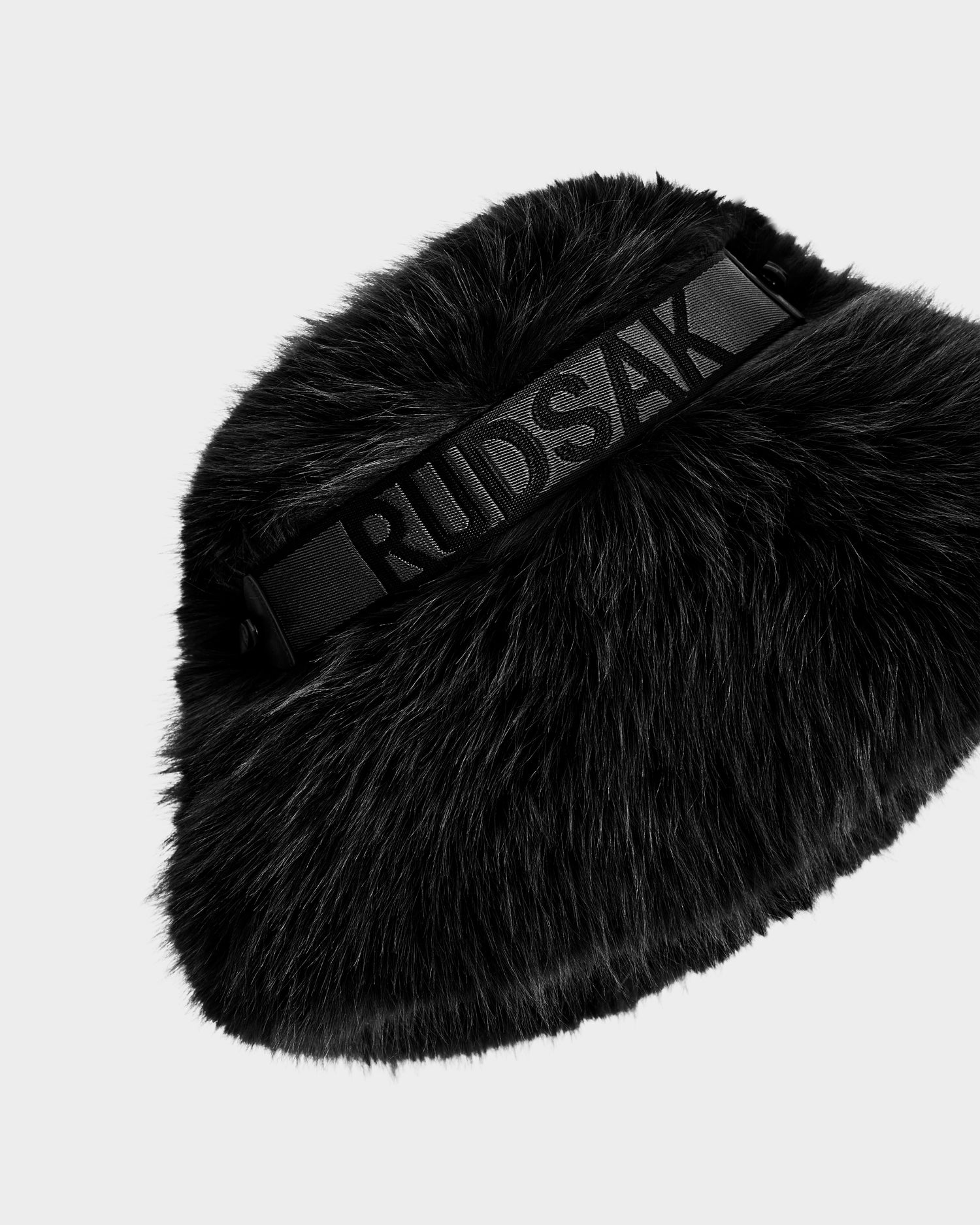 The ROMINA - 8425545 Black by Rudsak is a cozy, luxe faux fur women’s winter hat with a wide elastic band embossed with Rudsak, featuring a soft, plush texture and modern silhouette, shown on a plain white background.