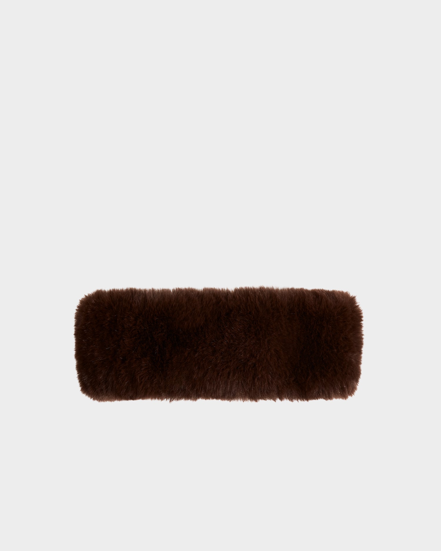 The SANDIE - L425552 Espresso cushion by Rudsak, a rectangular dark brown faux fur piece, is centered on a plain light gray background, evoking cozy winter style for any space.