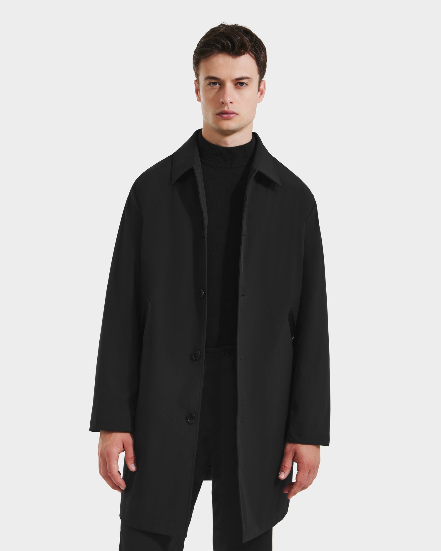 A man faces forward wearing the Rudsak STANTON - 6125531 Black men’s 3-in-1 overcoat with a quilted inner puffer jacket, styled over a black turtleneck and pants, set against a plain light gray background.