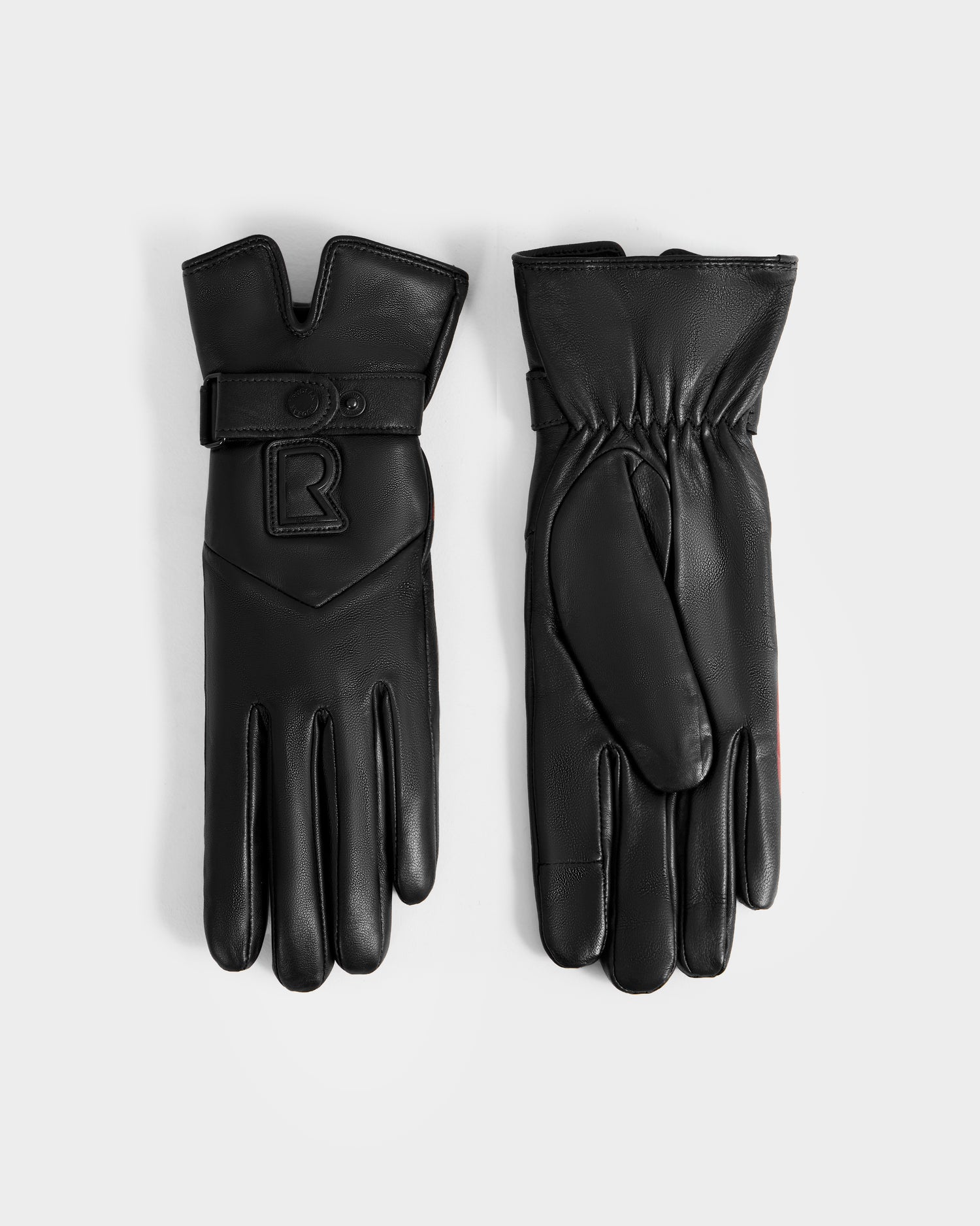 A pair of Rudsak STROMBOLI - 8424510 Black women's leather gloves is shown on a white background. One winter glove has a strap and R patch, while the other is palm up with wrist elastic.