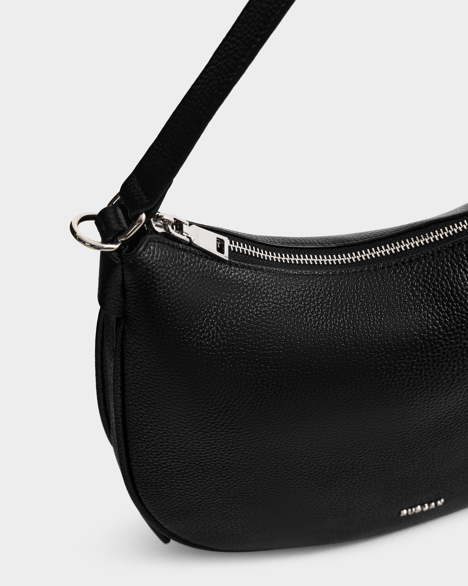 Close-up of the Rudsak SYLVIA - L325515 Black women’s leather shoulder bag, featuring a textured crescent silhouette, silver zipper, shoulder strap, and partial white brand name visible on the lower right side.