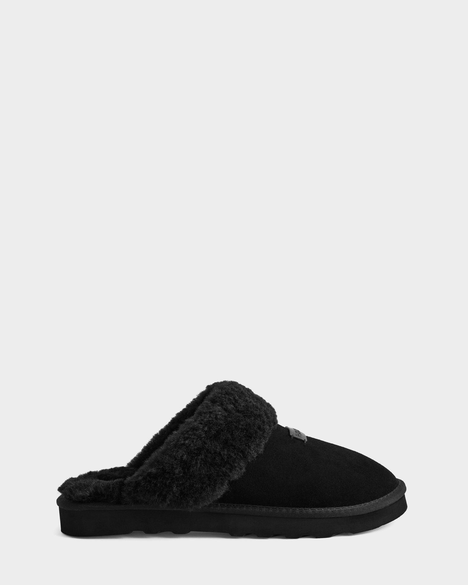 The Rudsak WILBER - 6225509 Black is a men's suede slipper with plush faux shearling lining and a flat sole, shown in side profile on a light gray background—ideal for comfortable loungewear.
