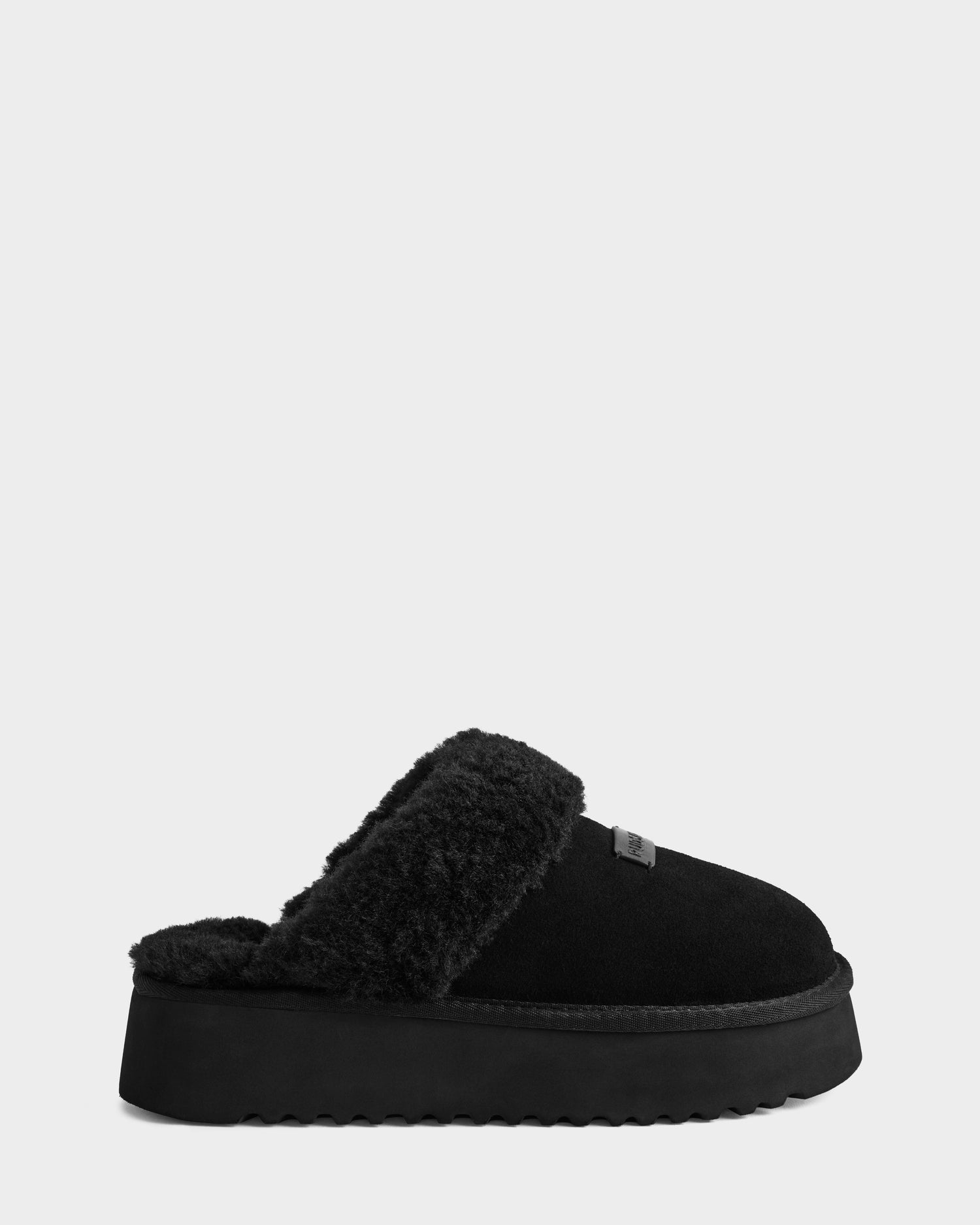 The Rudsak WILMA - 8225582 Black is a women's black suede slipper with a thick platform sole and fluffy lining around the opening, shown in side profile against a plain light gray background.