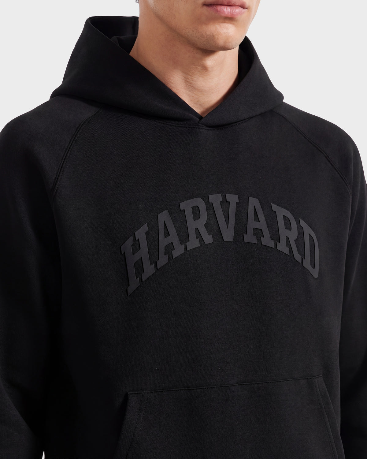 A person wearing Rudsak’s limited-edition BRIAR R HV - H525506 Black hoodie, featuring bold HARVARD lettering across the chest. The individual’s face is partially out of frame, and the look is finished with a subtle Rudsak-inspired flair.