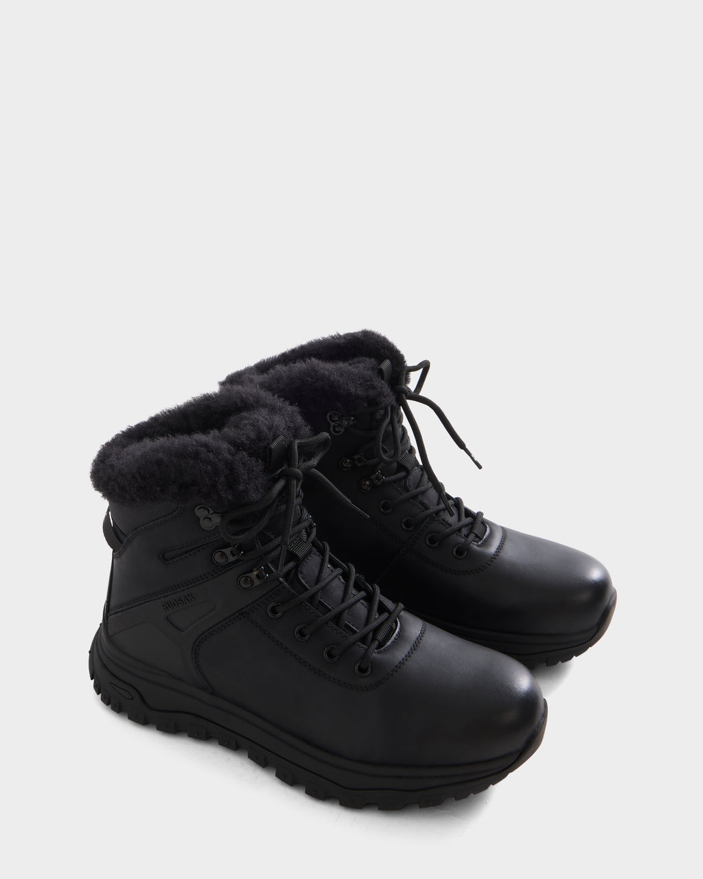 The BRYSON - 6226504 Black by Rudsak are black winter boots featuring a lace-up design, black faux fur lining, and a rugged, lugged outsole for outdoor use against a plain white background.