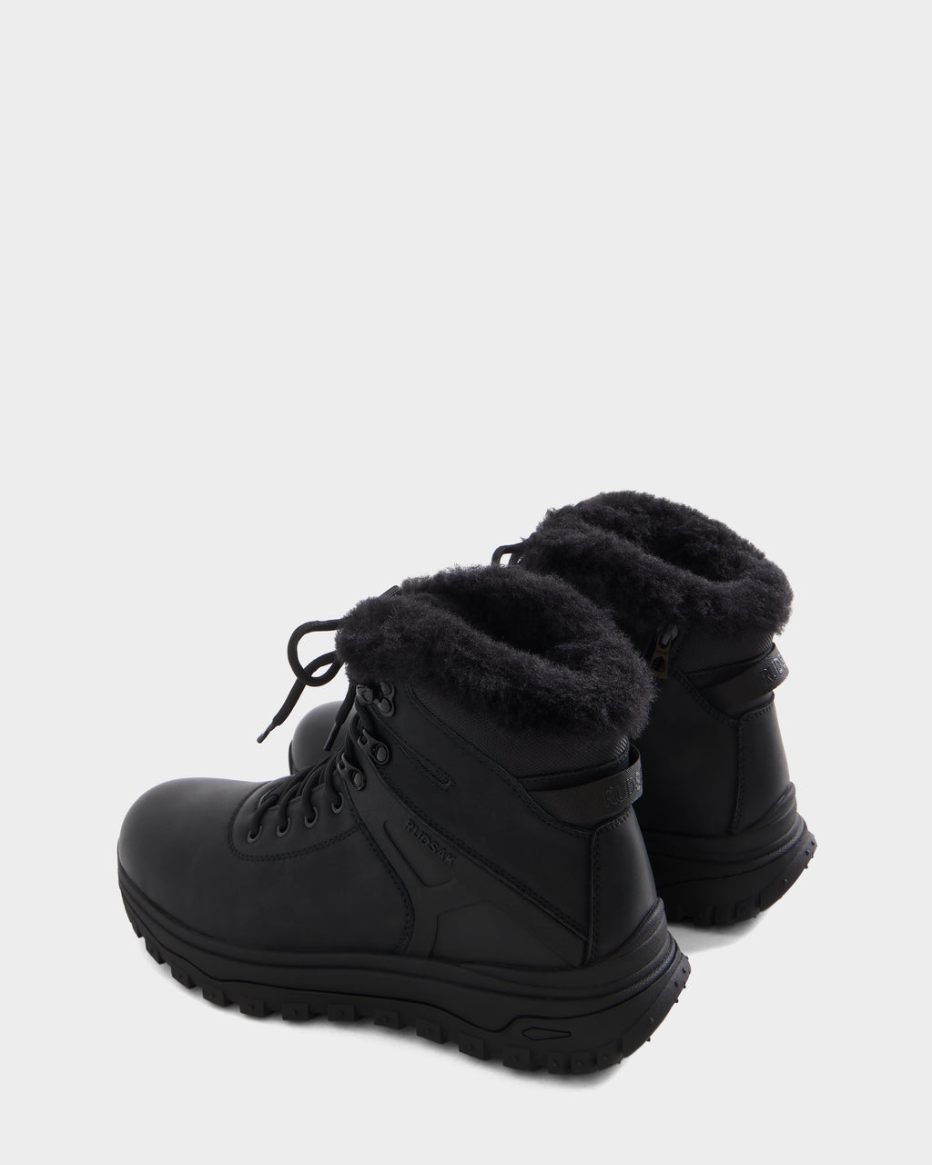 A pair of BRYSON - 6226504 Black winter boots by Rudsak with lace-up design, cozy faux fur lining, and rugged lugged outsole, shown side by side on a light gray background.