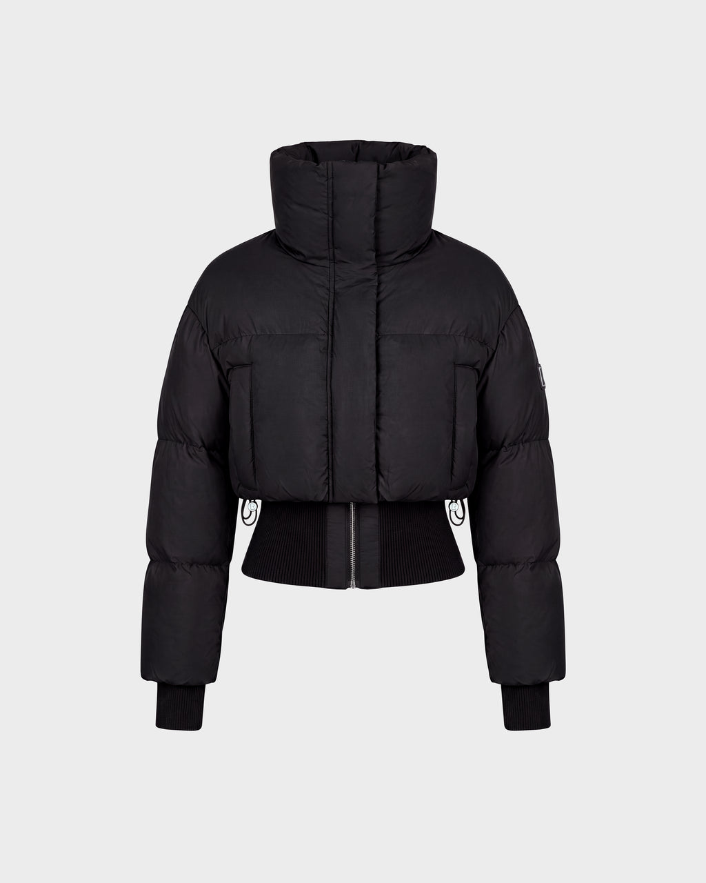 The Rudsak DONYA - 8126516 Black is a black cropped puffer jacket featuring a high collar, long sleeves, ribbed cuffs, and a front zipper, shown against a plain light gray background. Now available for pre-order; expected to ship by September 15th.