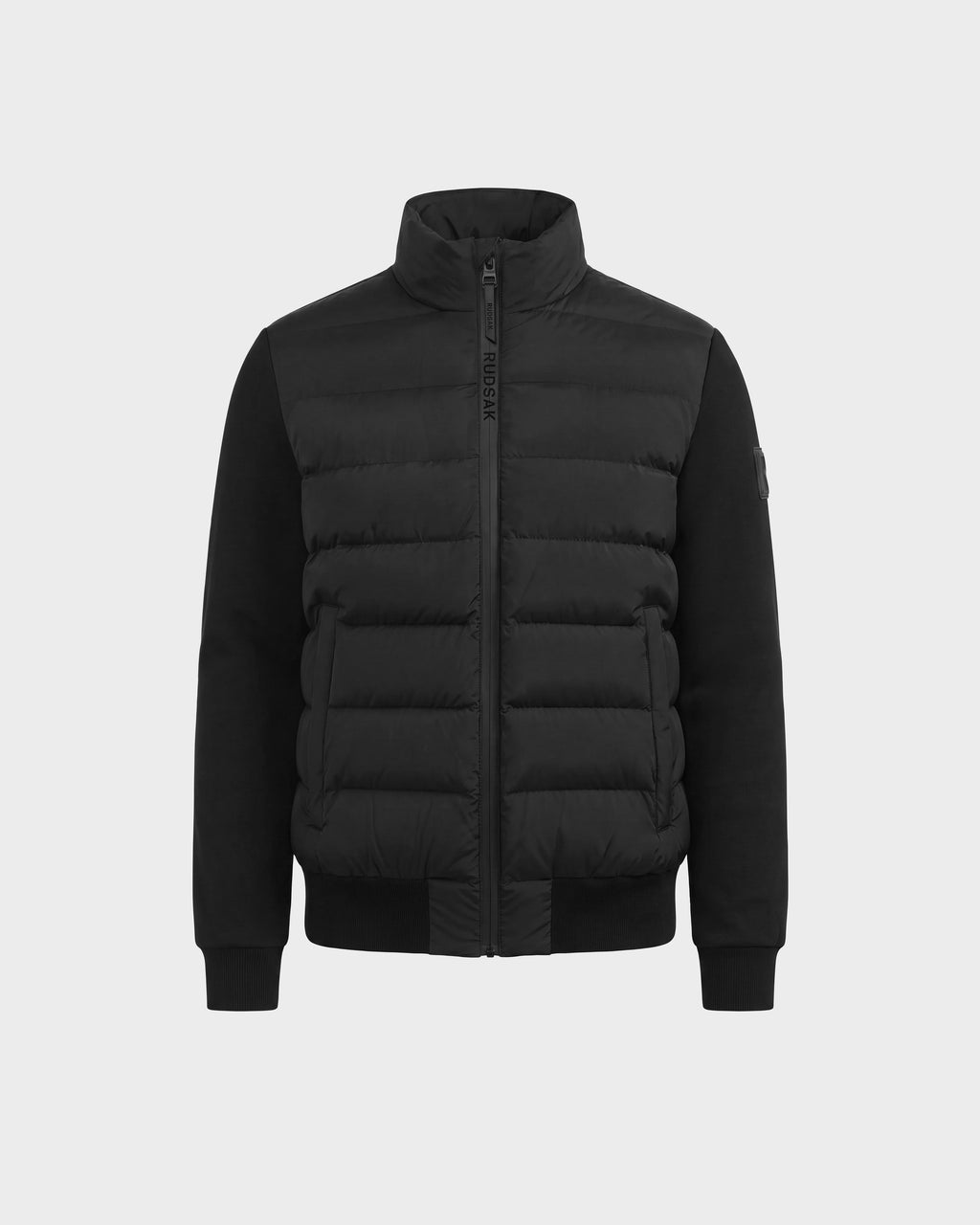 The EUGENE - 6124721 Black men's hybrid jacket by Rudsak features quilted padded sections on the front, smooth performance luxury fabric sleeves, a high collar, zip closure, and ribbed cuffs. This black puffer jacket is displayed against a plain light background.