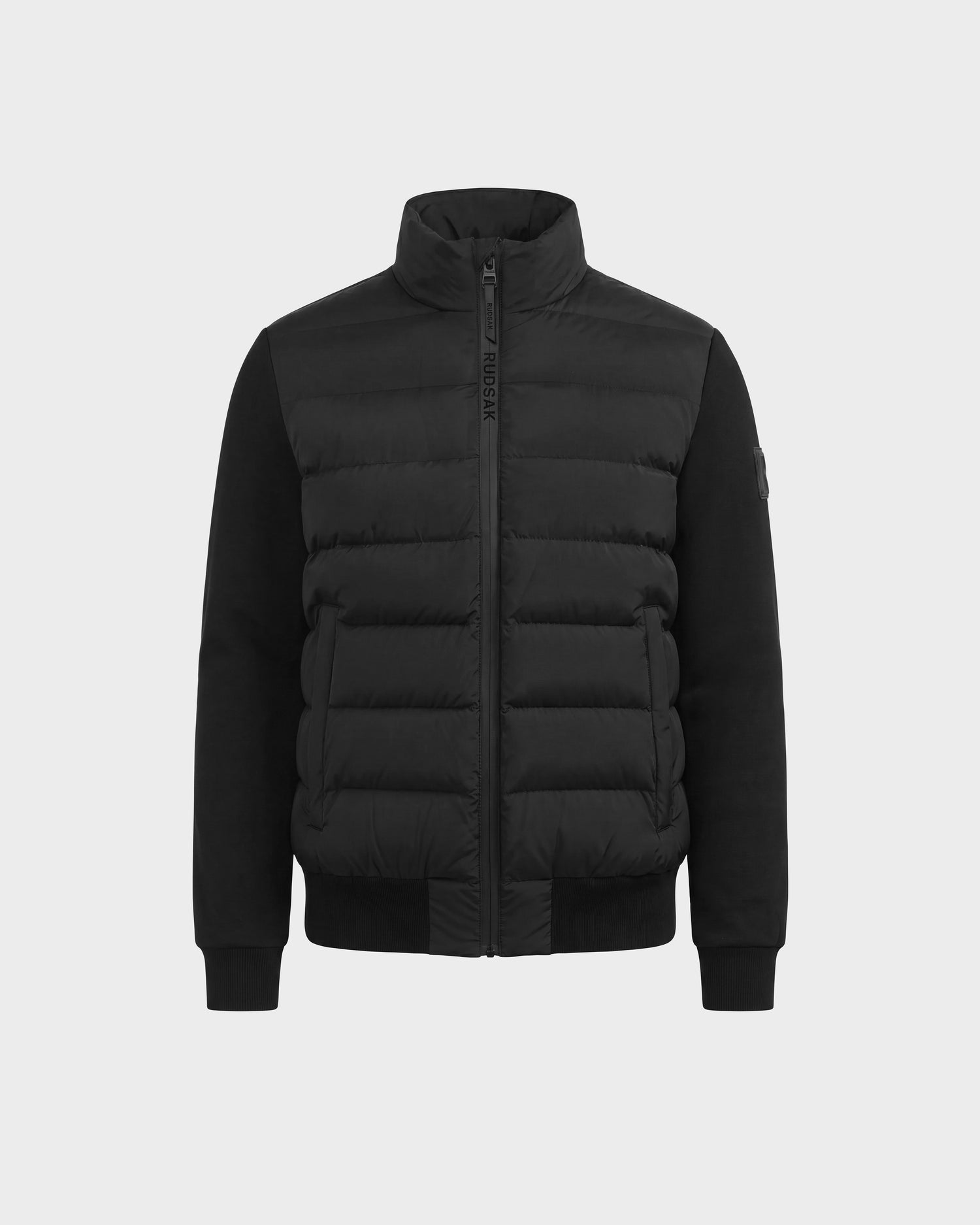 The Rudsak EUGENE - 6124721 Black men's hybrid jacket features a high collar, front zipper closure, and ribbed cuffs. Crafted from lightweight mixed-media fabrics for versatile performance luxury, it is displayed on a plain white background.
