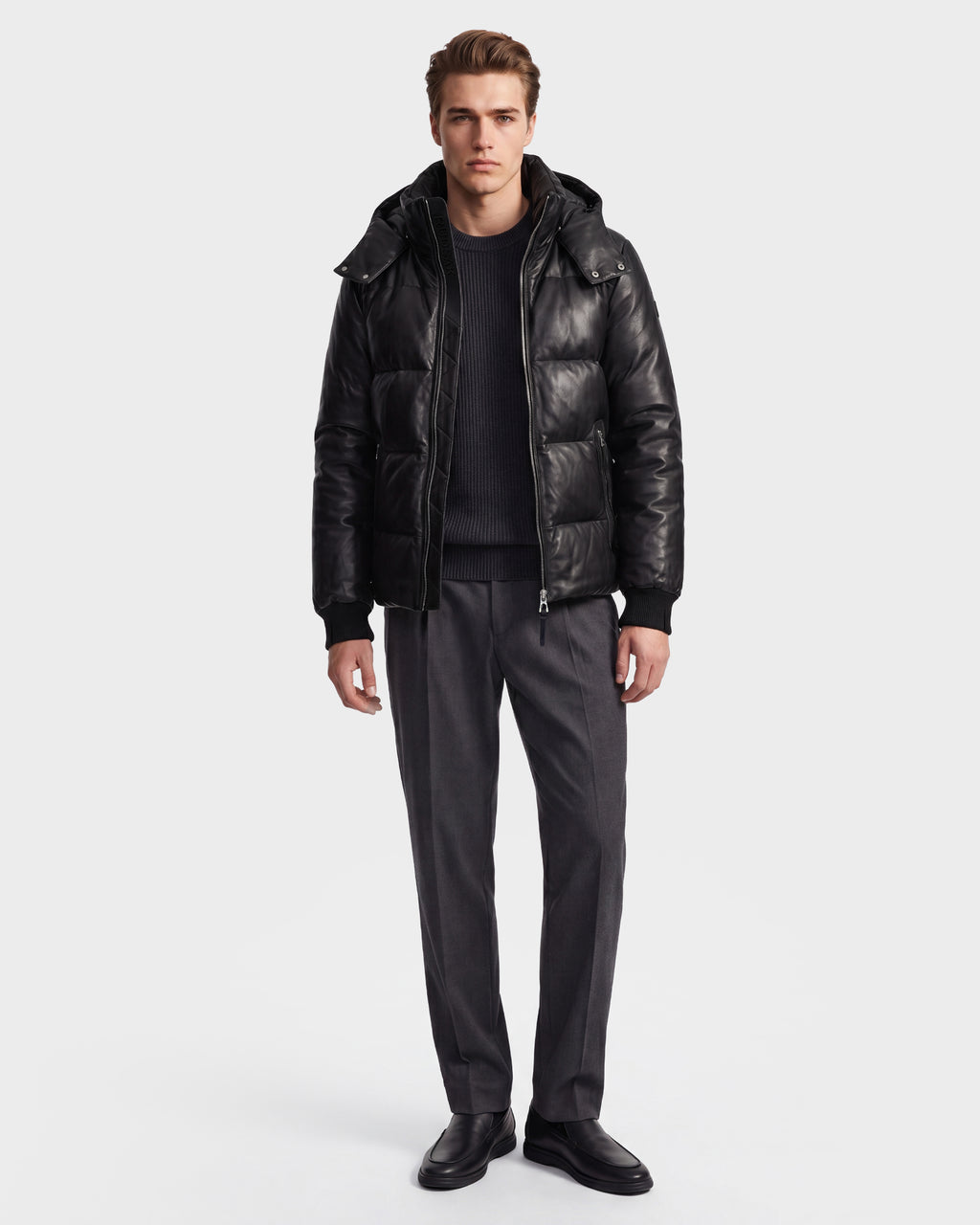 A person wearing the Rudsak HARVEY X - 6125681 Black puffer jacket, a black sweater, gray trousers, and black shoes stands facing forward against a plain white background.
