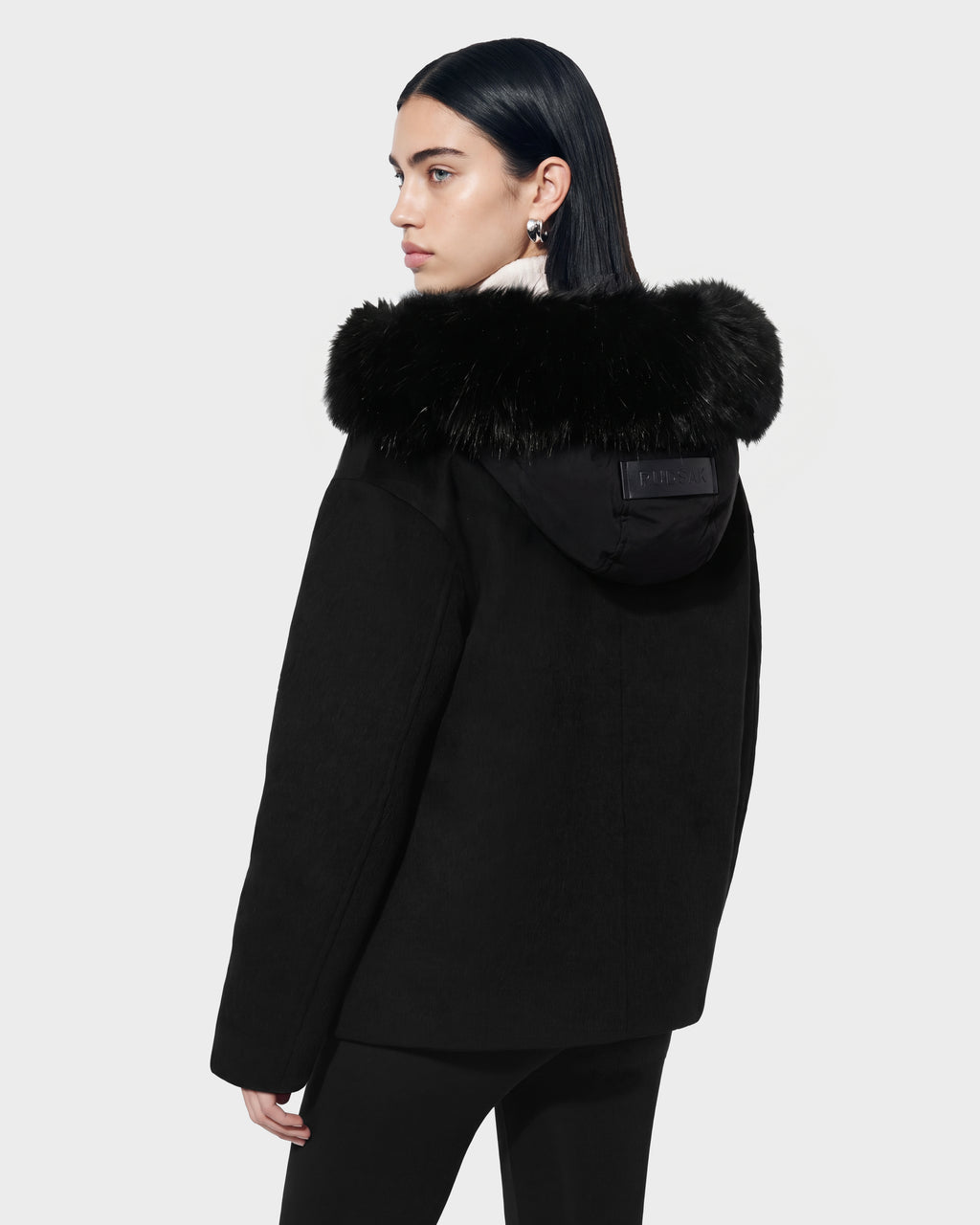 A person wearing a black Rudsak HAZEL - 8126981 wool-blend winter coat with a faux-fur trim on the hood.