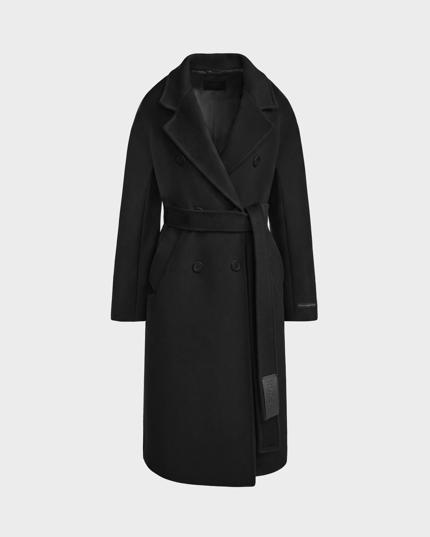 The KOURT W - 8124702 Black by Rudsak is a long black coat crafted from premium wool, featuring a wide lapel, double-breasted buttons, and a matching belt tied at the waist. This tailored belted wool coat includes side pockets and showcases a classic design, set against a plain, light background.