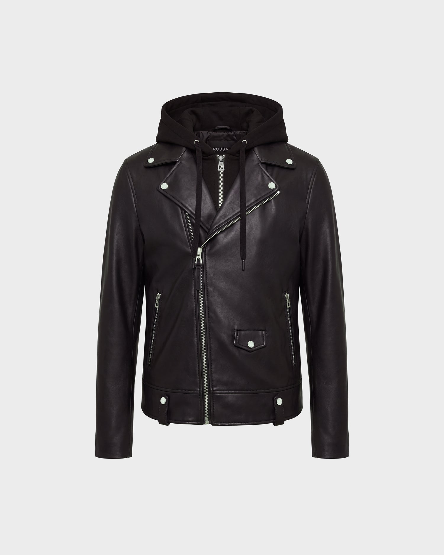 The MANUS - 6124600 Black leather biker jacket by Rudsak features silver zippers and buttons, along with a removable hooded dickie attached beneath the collar. Displayed against a plain light gray background, this men's moto jacket offers a sleek and versatile look.