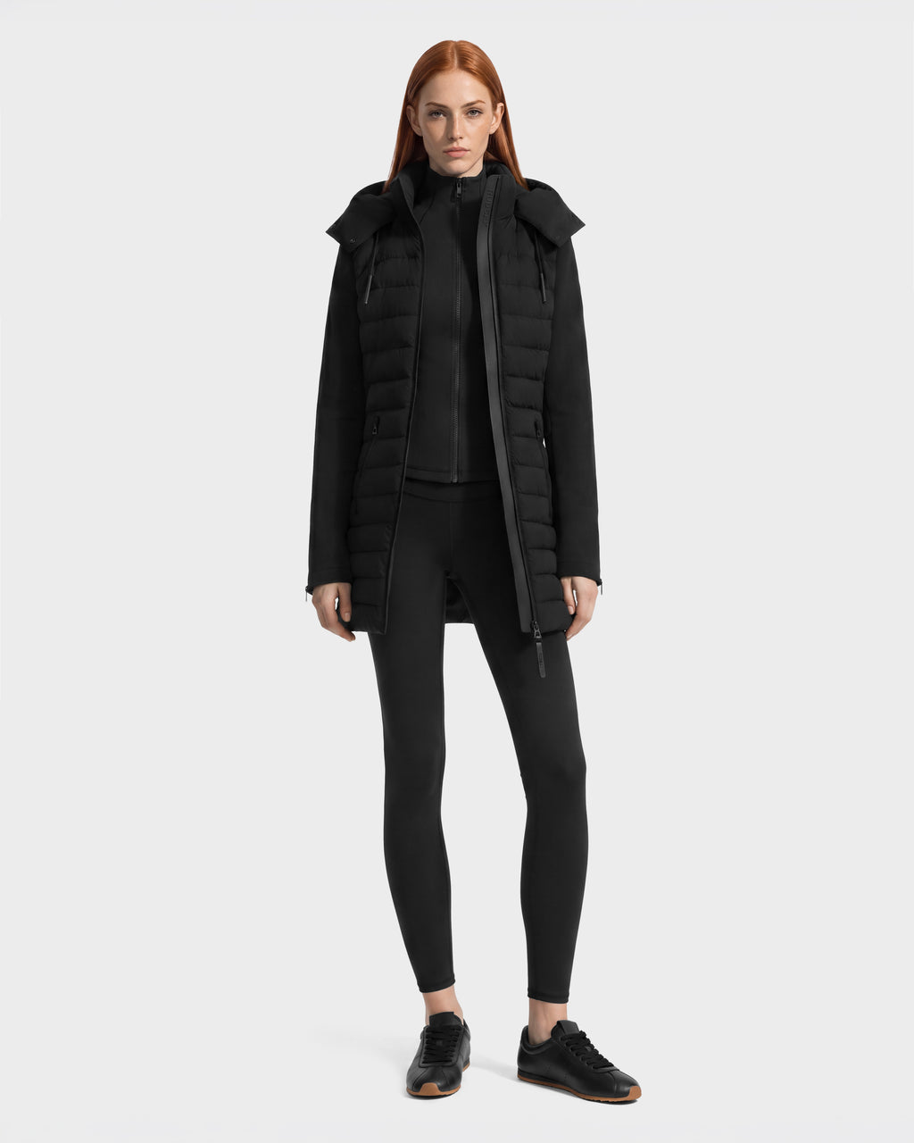 A person wearing a black Rudsak MERINA - 8125056 transitional hooded jacket over a matching zip-up, leggings, and black sneakers.