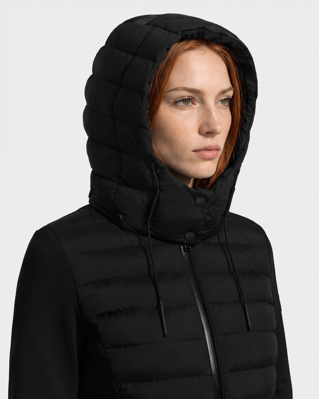 A woman wearing a black Rudsak MERINA - 8125056 hooded quilted down jacket with a front zipper.