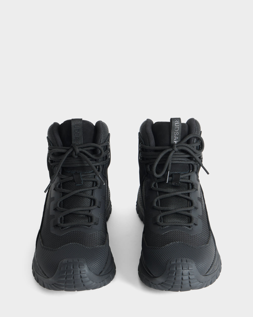 A pair of Rudsak REXON - 6226503 black high-top sneakers featuring thick rubber soles, black laces, and forward-facing tongue tabs displayed on a plain white background.