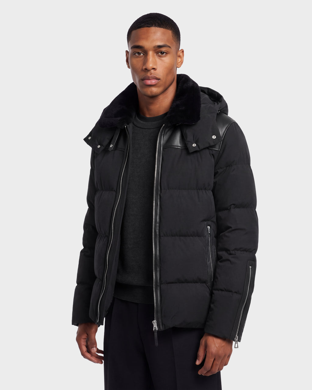 A man wears a black Rudsak SIMON PX - 6126503 Black quilted puffer jacket featuring leather accents and a fur-lined hood.