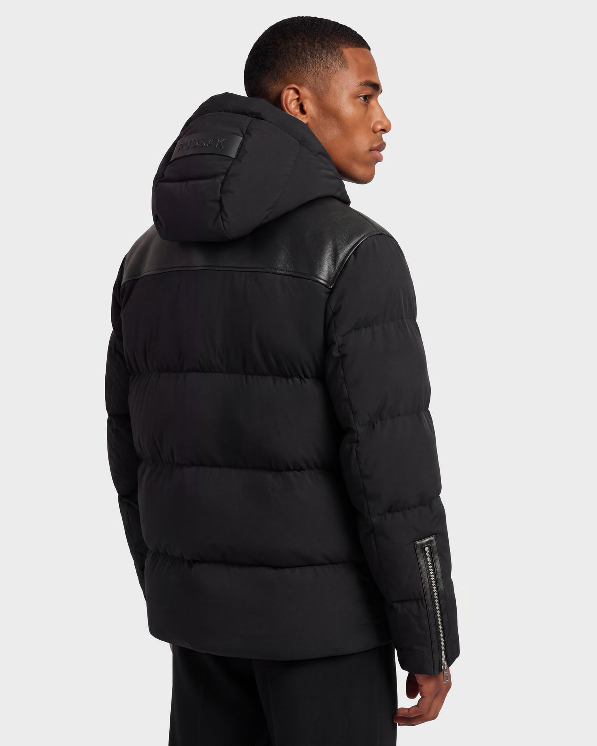 A person seen from the back wearing a black SIMON PX - 6126503 Black quilted puffer jacket with a hood and leather shoulder detailing.