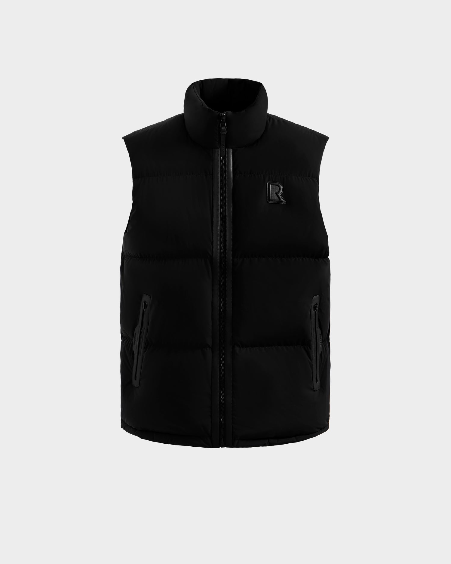 The FREDDY - 6125571 Black by Rudsak is a men’s black sleeveless puffer vest with a high collar, front zipper, two zippered side pockets, and a small R logo on the chest—perfect for lightweight layering, shown on a plain light background.