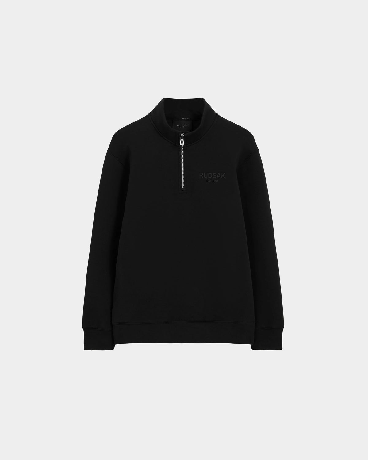 The Rudsak FREMONT - 9525000 Black M is a unisex quarter-zip sweater with a stand collar and long sleeves, made from a premium cotton blend, featuring subtle branding on the left chest, shown on a plain light gray background.