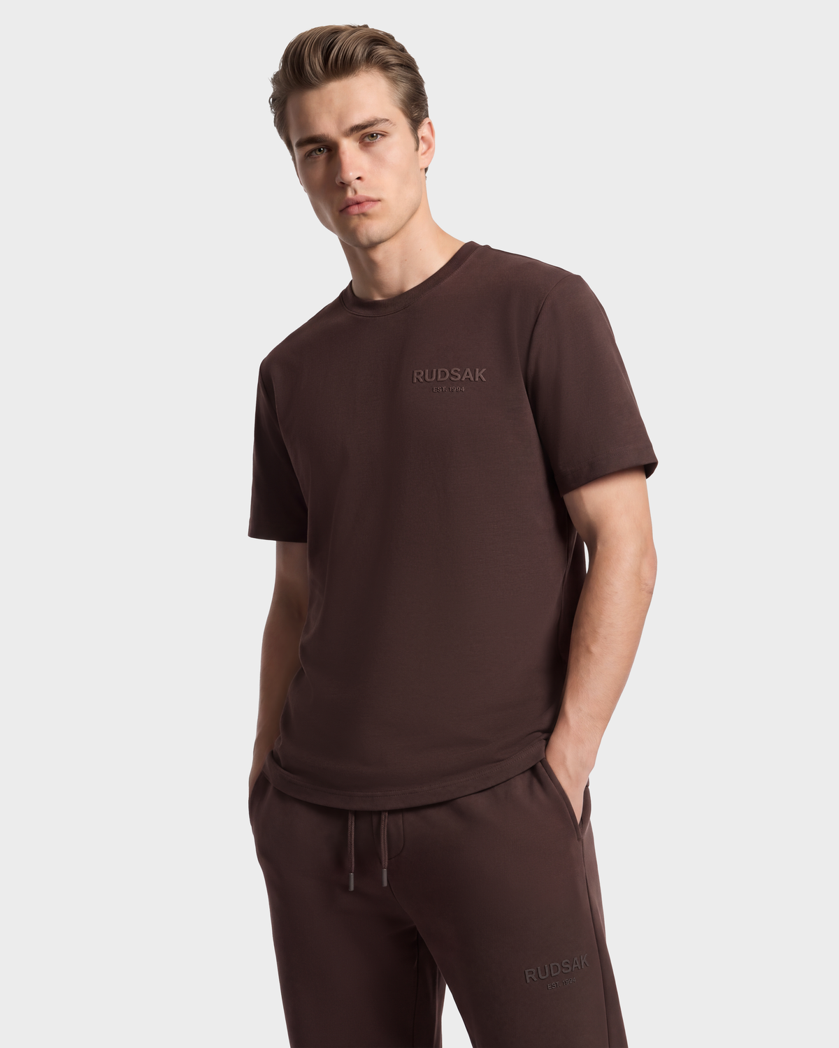 A man wearing the GRANT - 6525036 Espresso premium cotton crewneck t-shirt and matching dark brown drawstring sweatpants.