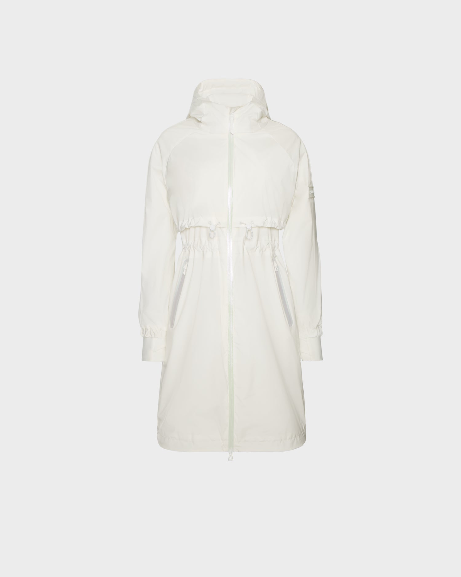 The Rudsak GRAYCE - 8124003 Cotton White is a women's long white windbreaker raincoat with a front zipper, drawstring waist, and two zippered pockets, shown against a plain light gray background.