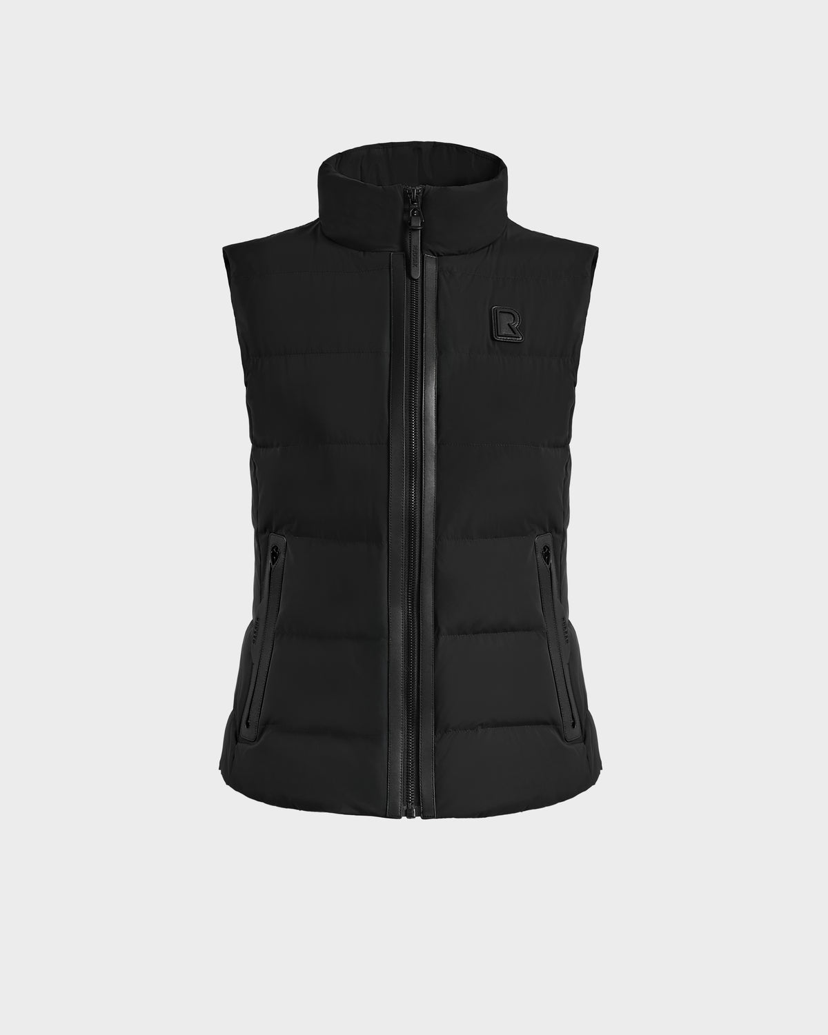 The Rudsak GABRIELA - 8125014 Black is a lightweight puffer vest with a high collar, front zipper, two zippered side pockets, and a subtle logo on the left chest, shown against a plain light background.