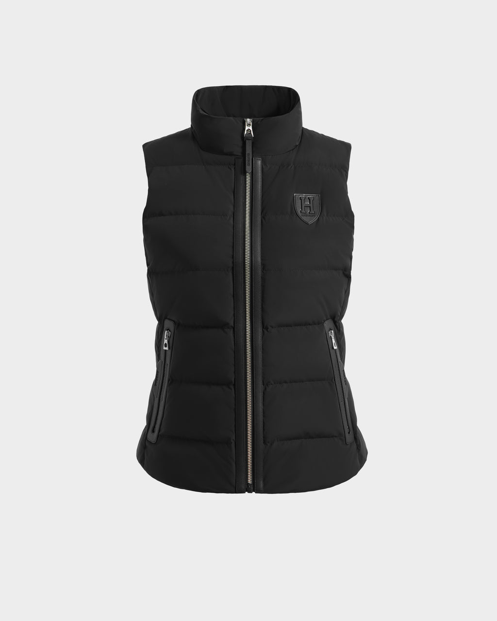 The GABRIELA HV - H125507 Black by Rudsak is a limited-edition black sleeveless quilted puffer vest with a high collar, front zipper, side zip pockets, and a small embossed logo on the left chest, from the Harvard x RUDSAK collection.