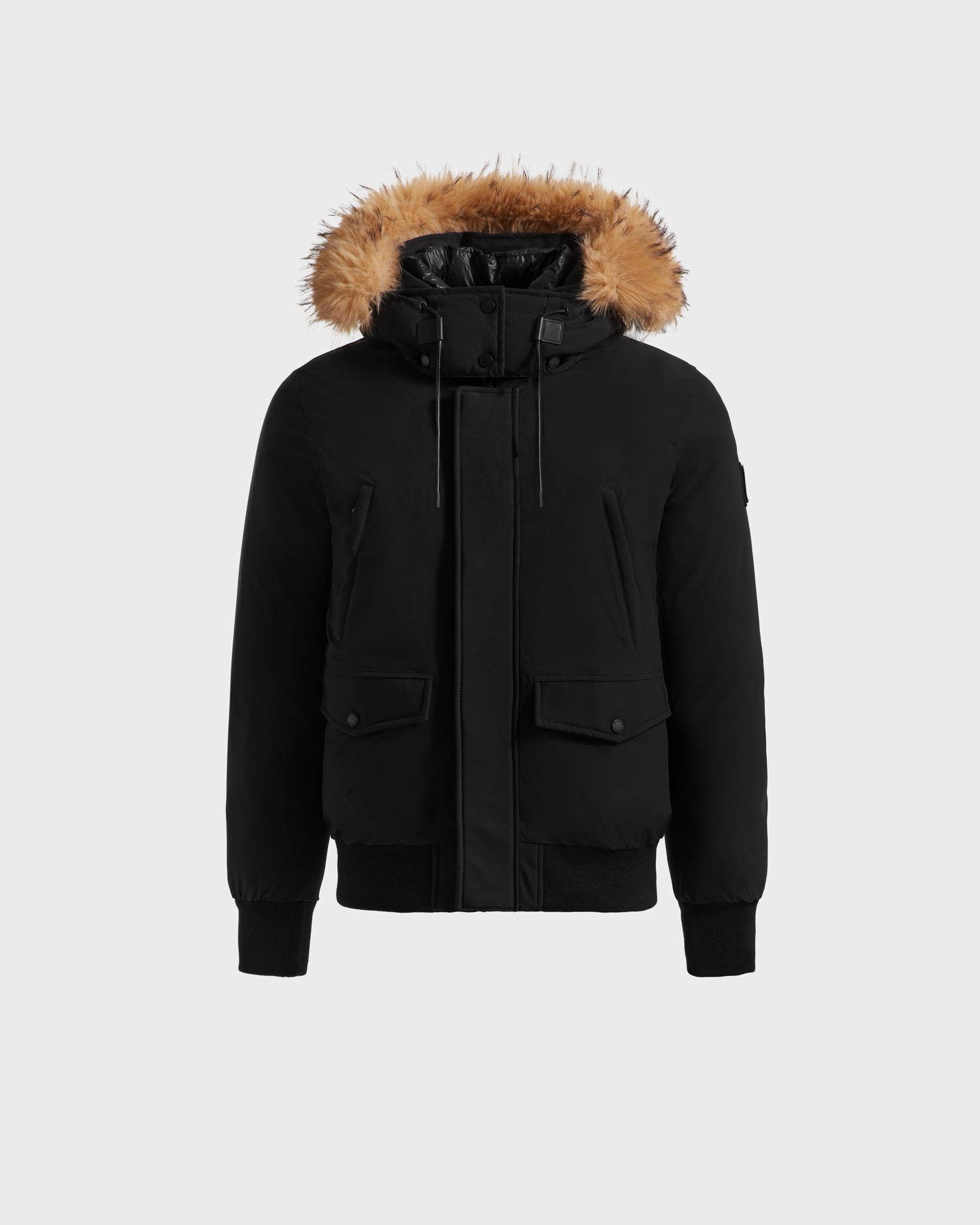 The Rudsak GEORGE - M125511 Black men's winter down bomber features premium down fill, front zipper and button closure, two front flap pockets, chest pockets, ribbed cuffs and hem, and a hood with brown faux fur trim. Displayed on a plain light background.
