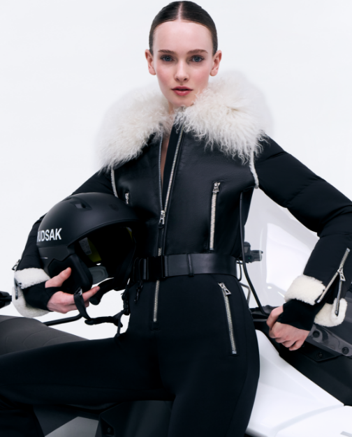 Person wearing a black outfit with white fur trim, holding a helmet, on a white background.