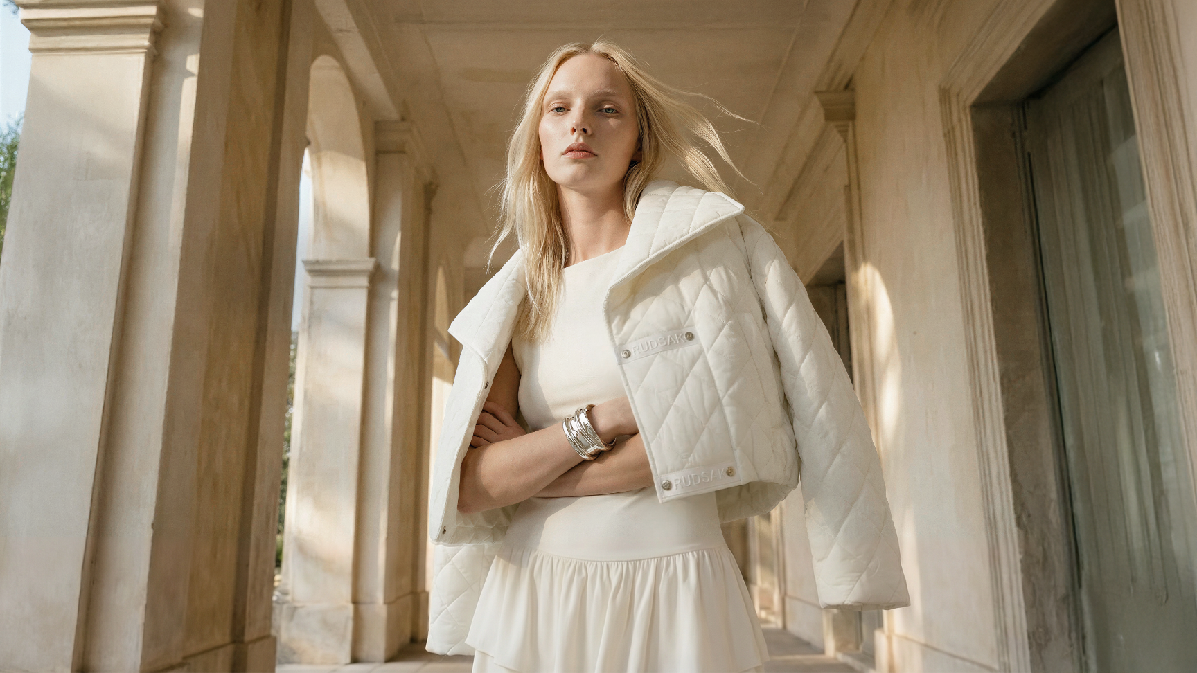 Woman in a white coat standing in front of classical architecture