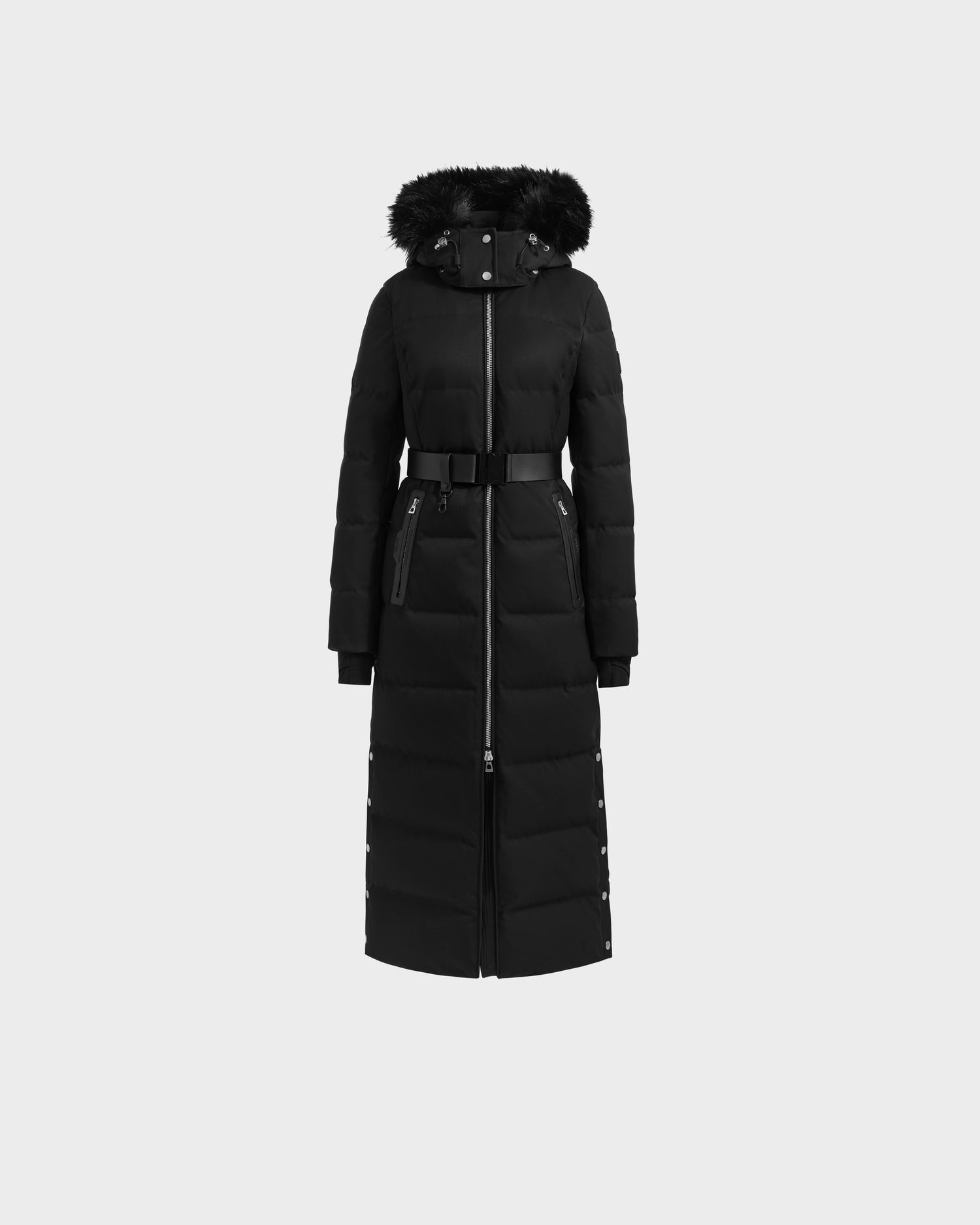 The Rudsak IZABELLA H - 8125644 Black is a long women’s puffer featuring a belted waist, detachable black fur-trimmed hood, front zipper, and snap buttons at the sides—perfect for chic warmth on chilly days. Displayed on a light gray background.