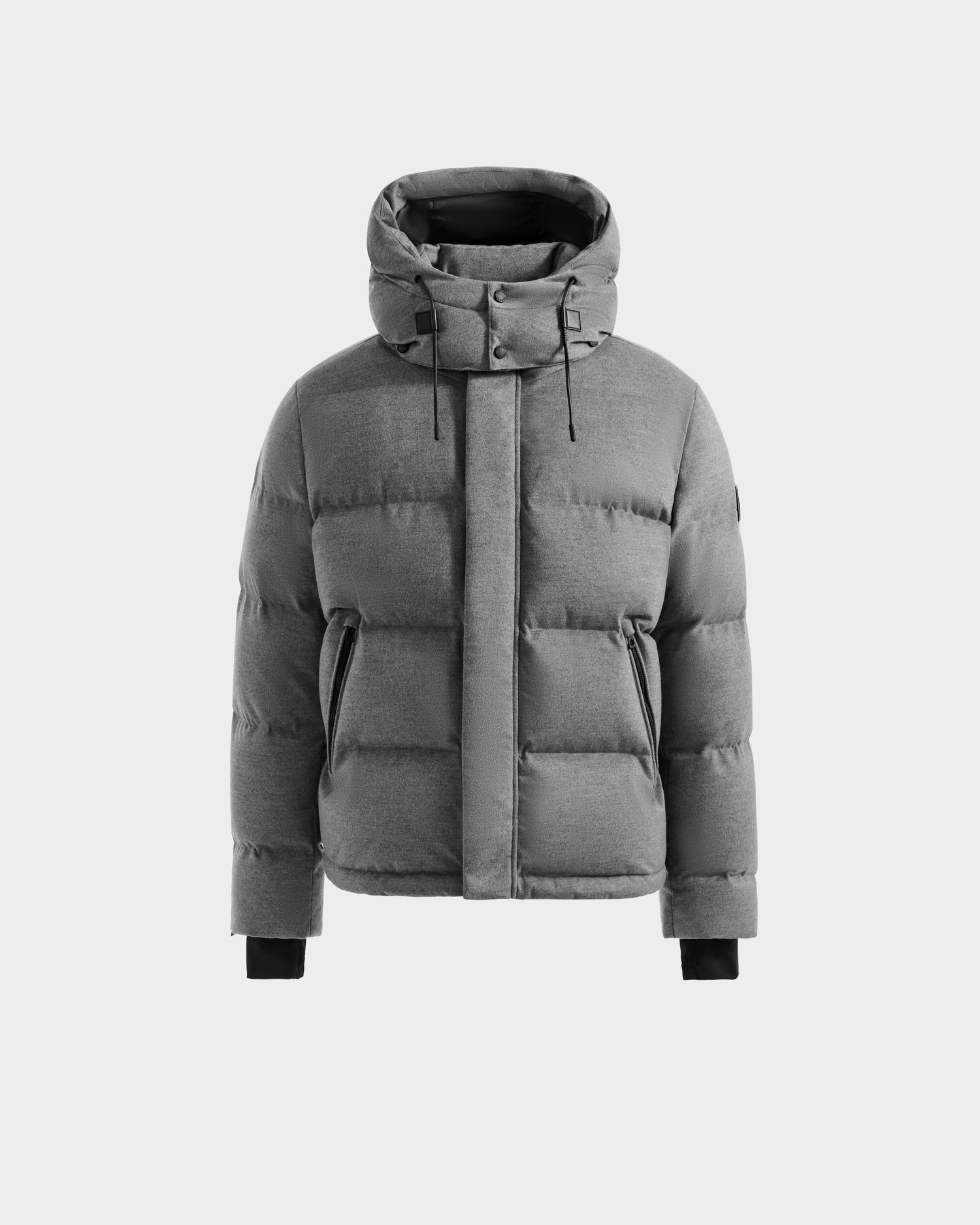 The Rudsak JOEL W - 6125683 Heather Charcoal is a men’s gray wool-blend down puffer jacket featuring a high collar, removable hood, snap placket over the front zipper, side zip pockets, and black ribbed cuffs, shown on a light gray background.