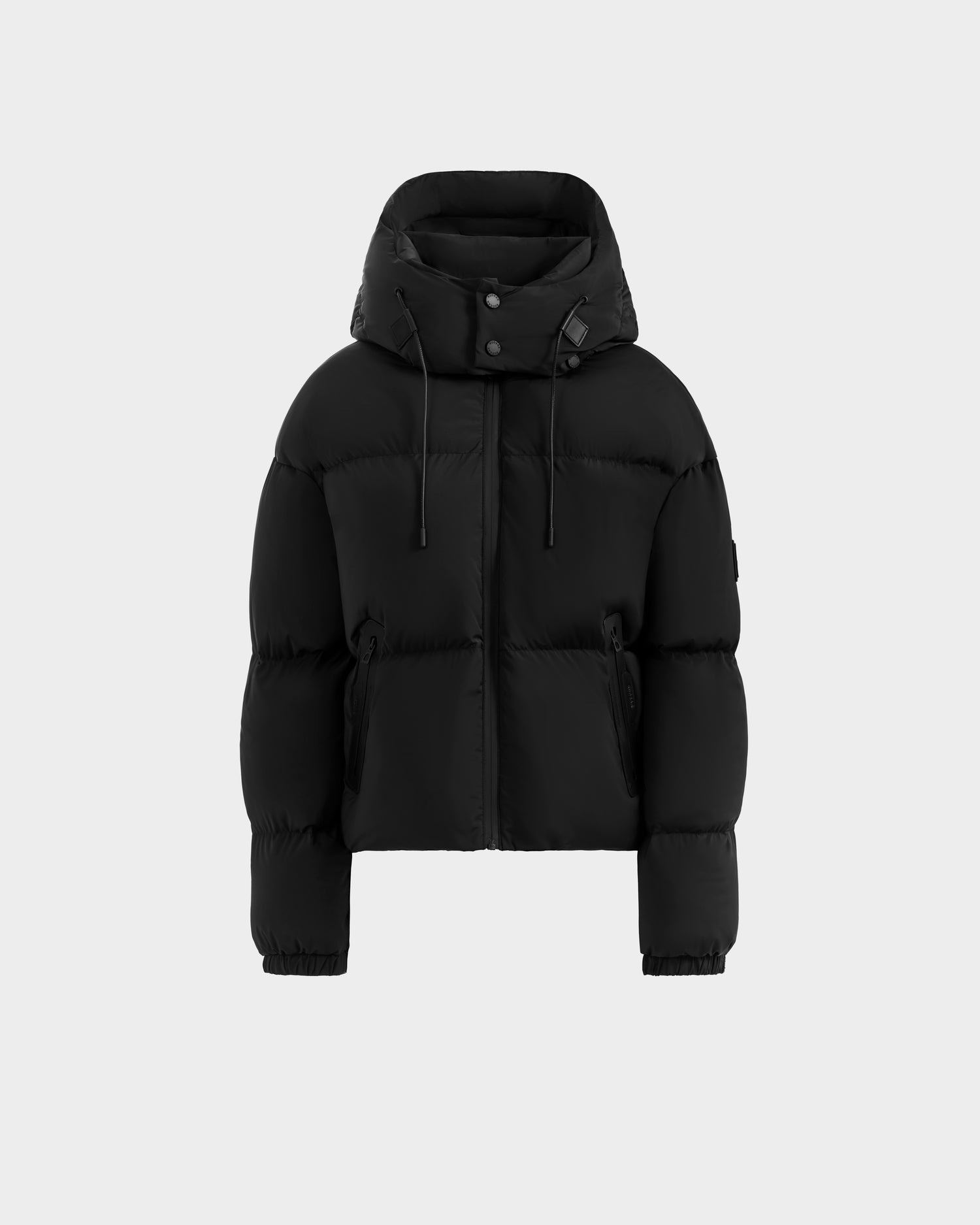 The Rudsak KARLEE S - 8125699 Black women’s down puffer jacket features a hood, front zipper, snap buttons, two zippered side pockets, and elastic cuffs—an ideal cold-weather essential shown on a light grey background.