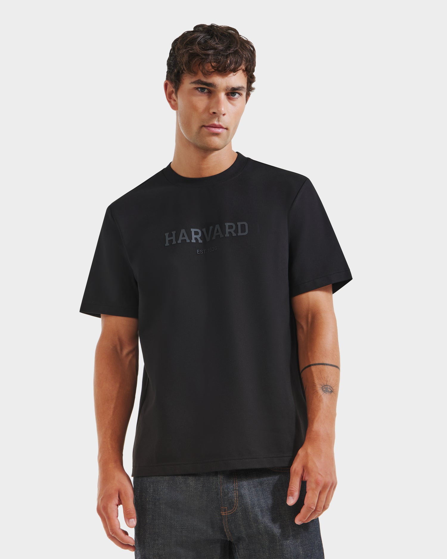 A man wearing a Rudsak KARTER R HV - H525507 Black T-shirt and dark jeans stands facing forward against a plain white background, showcasing classic streetwear style.