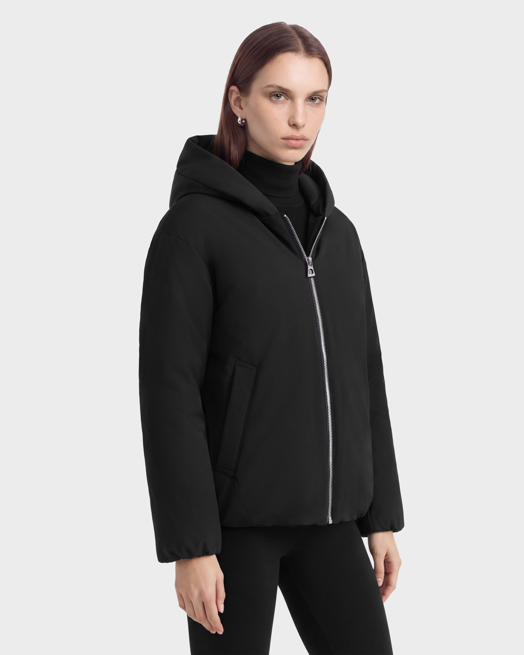 A person wearing a black Rudsak KATHLEEN - 8126764 hooded puffer jacket with a silver front zipper.
