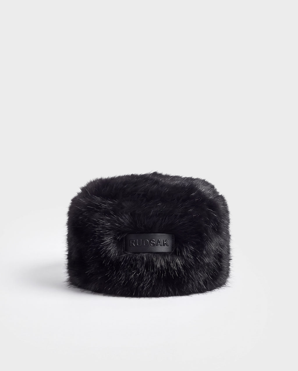Black faux fur LORETTA - 8426503 Black pillbox hat with a centered rectangular leather patch embossed with the Rudsak brand name.