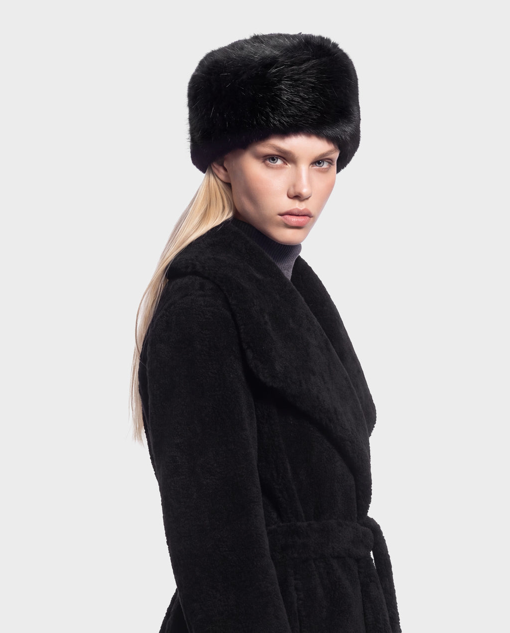 A person wearing a LORETTA - 8426503 Black coat with a black fur hat, a wide collar, and a belted waist.