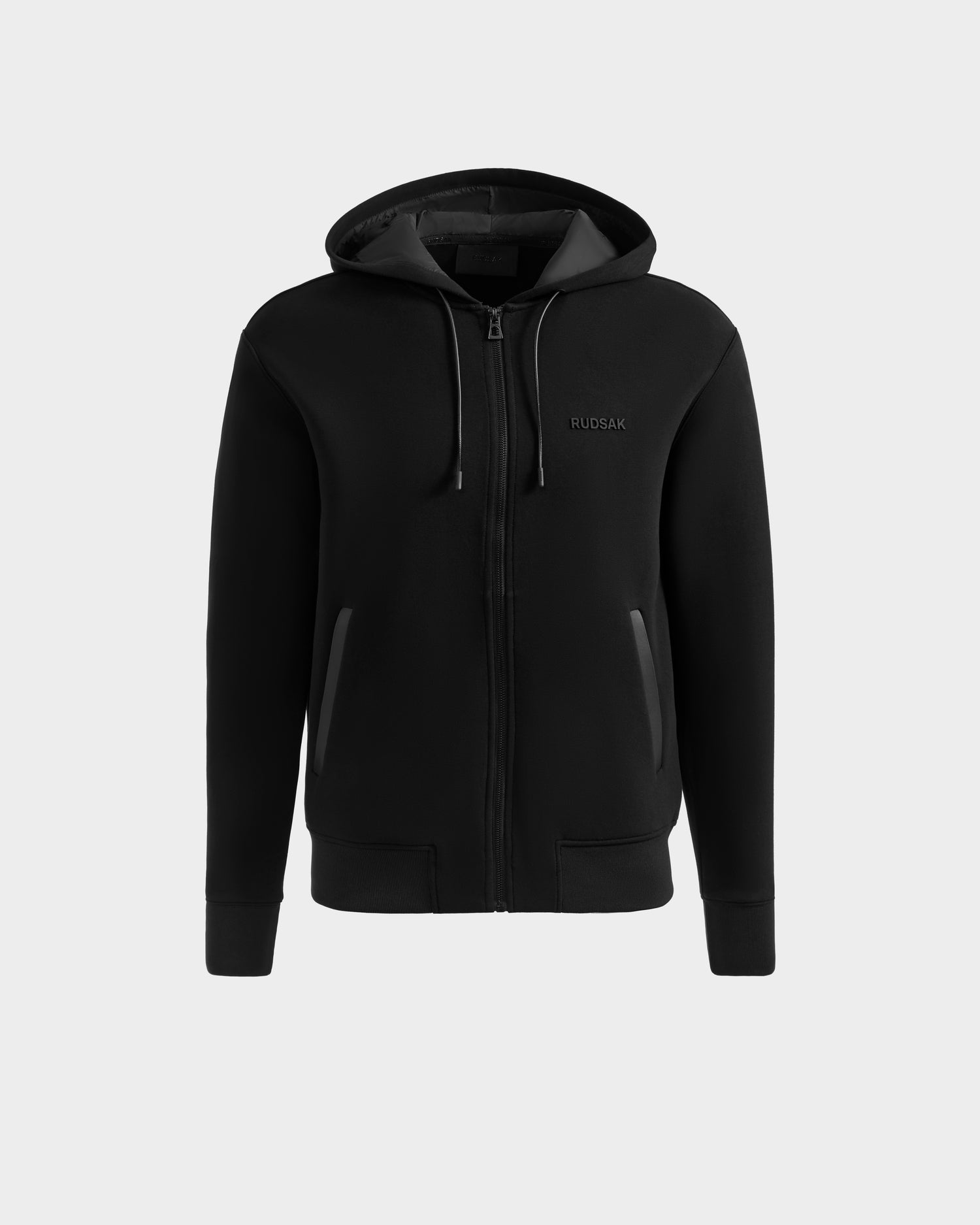 The Rudsak LEVI - 9525552 Black M is a unisex zip-up hoodie with a front zipper, side pockets, drawstring hood, vegan leather trims, and subtle Rudsak embroidery on the left chest.