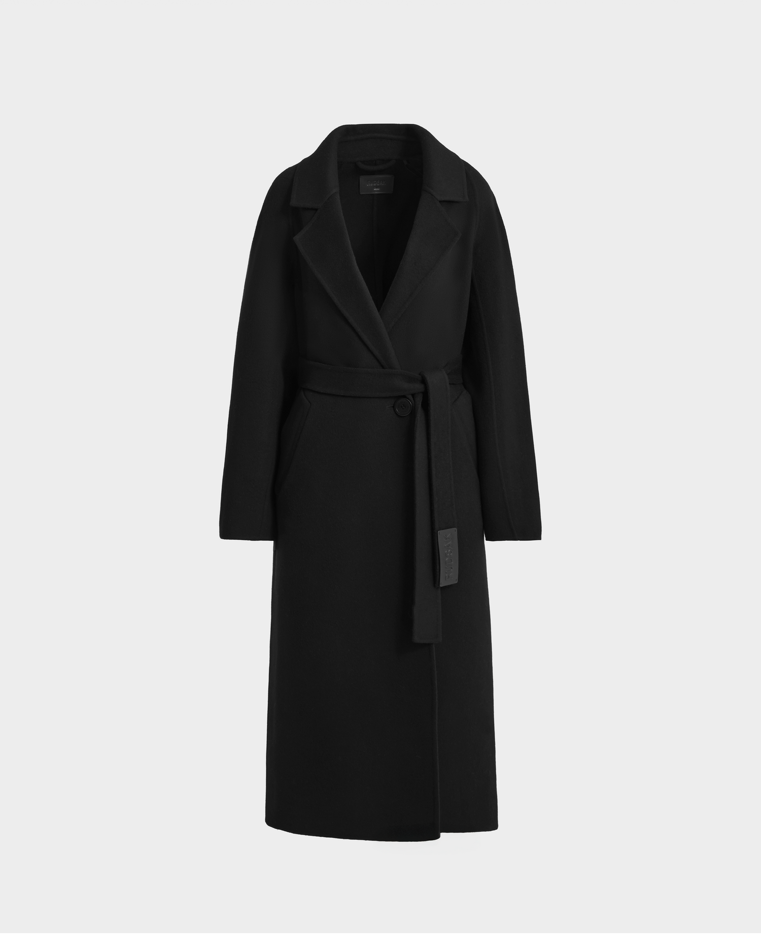 The Rudsak LILIA - 8125634 Black is a women’s long wrap coat in wool, silk, and cashmere with a wide lapel collar and matching belt, shown elegantly against a plain light gray background.