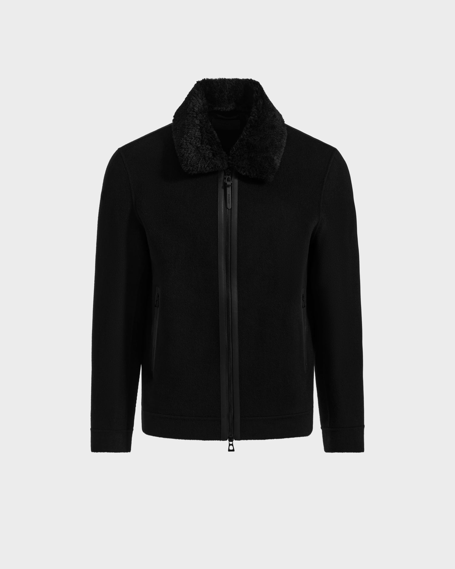 The Rudsak LINCOLN - 6125038 Black men’s coat features a front zipper, side pockets, and a removable soft faux fur collar, shown against a plain light gray background.