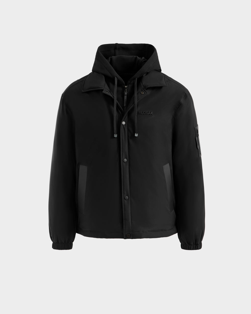 The Rudsak LUCA - 6125009 Black is a weather-resistant men’s jacket with hood, high collar, front snap buttons, zipper closure, adjustable drawstrings, two side pockets, left sleeve pocket, and elastic cuffs.