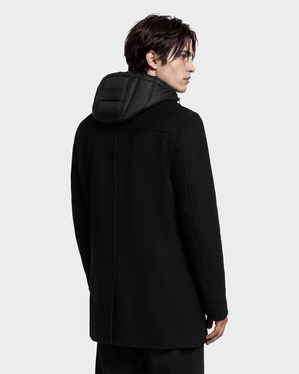 A man seen from the back wearing a black LUCIEN - 6126508 Black coat with a quilted hood.