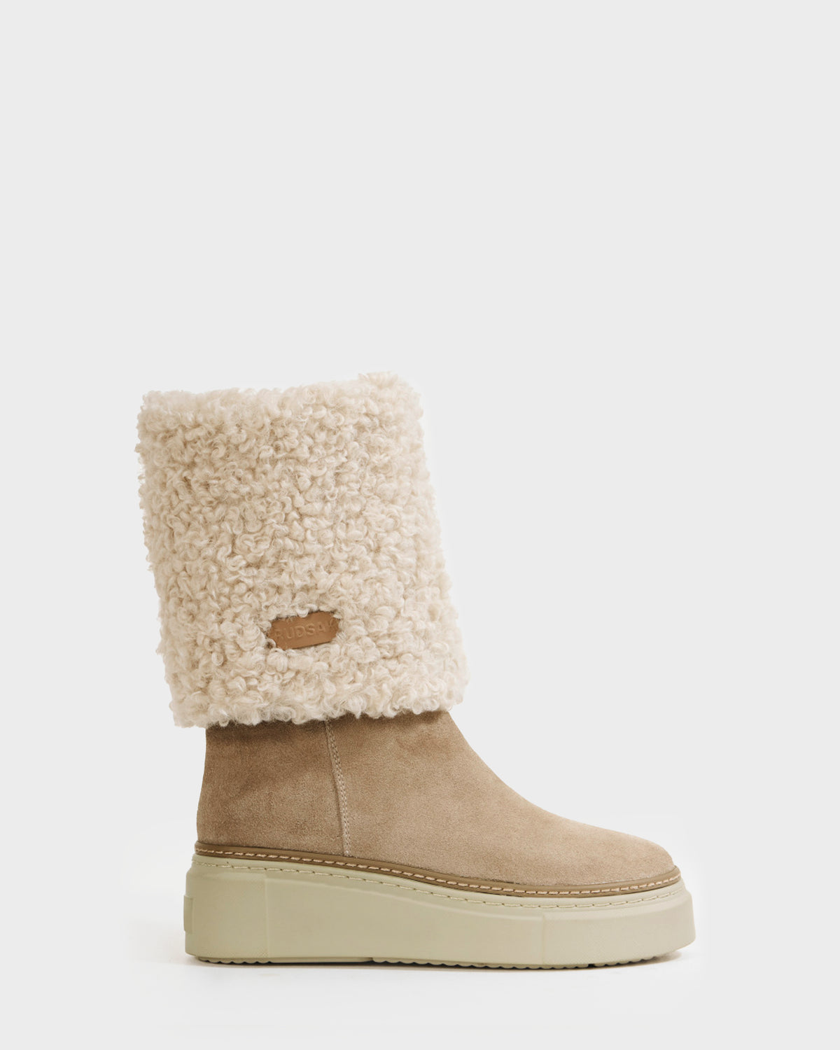 The Rudsak MIKIE - 8225579 Almond is a tan women's suede boot with a thick beige platform sole and a tall, textured cream shearling cuff featuring a small leather patch, displayed against a plain white background.