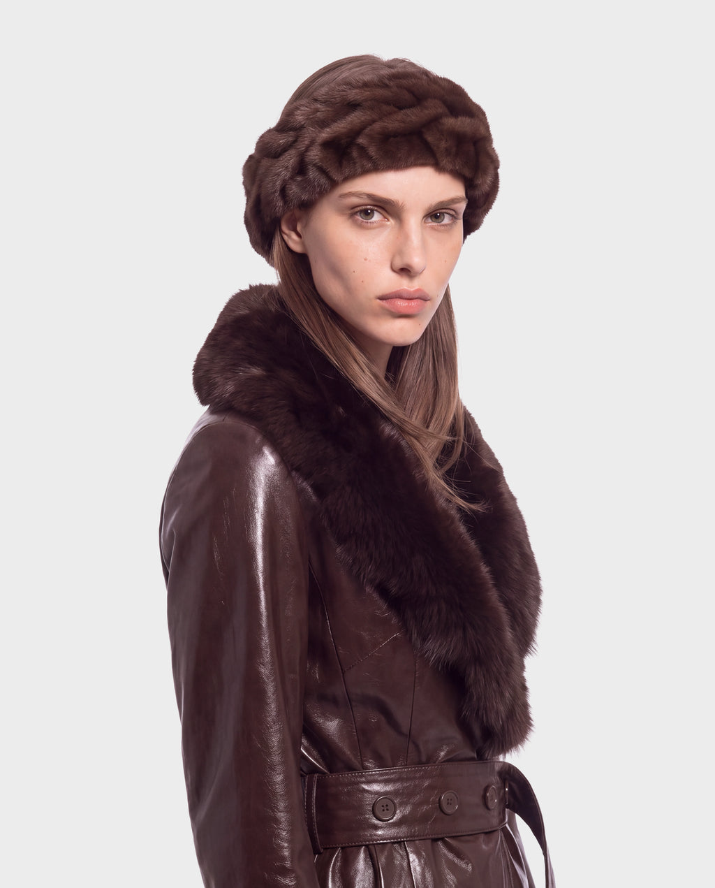 A person wearing a MILA - 8426518 Espresso dark brown leather coat with a fur-trimmed collar and a matching fur headband.